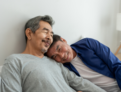 Asian elderly male gay couple lying down on bed and hugging each other.