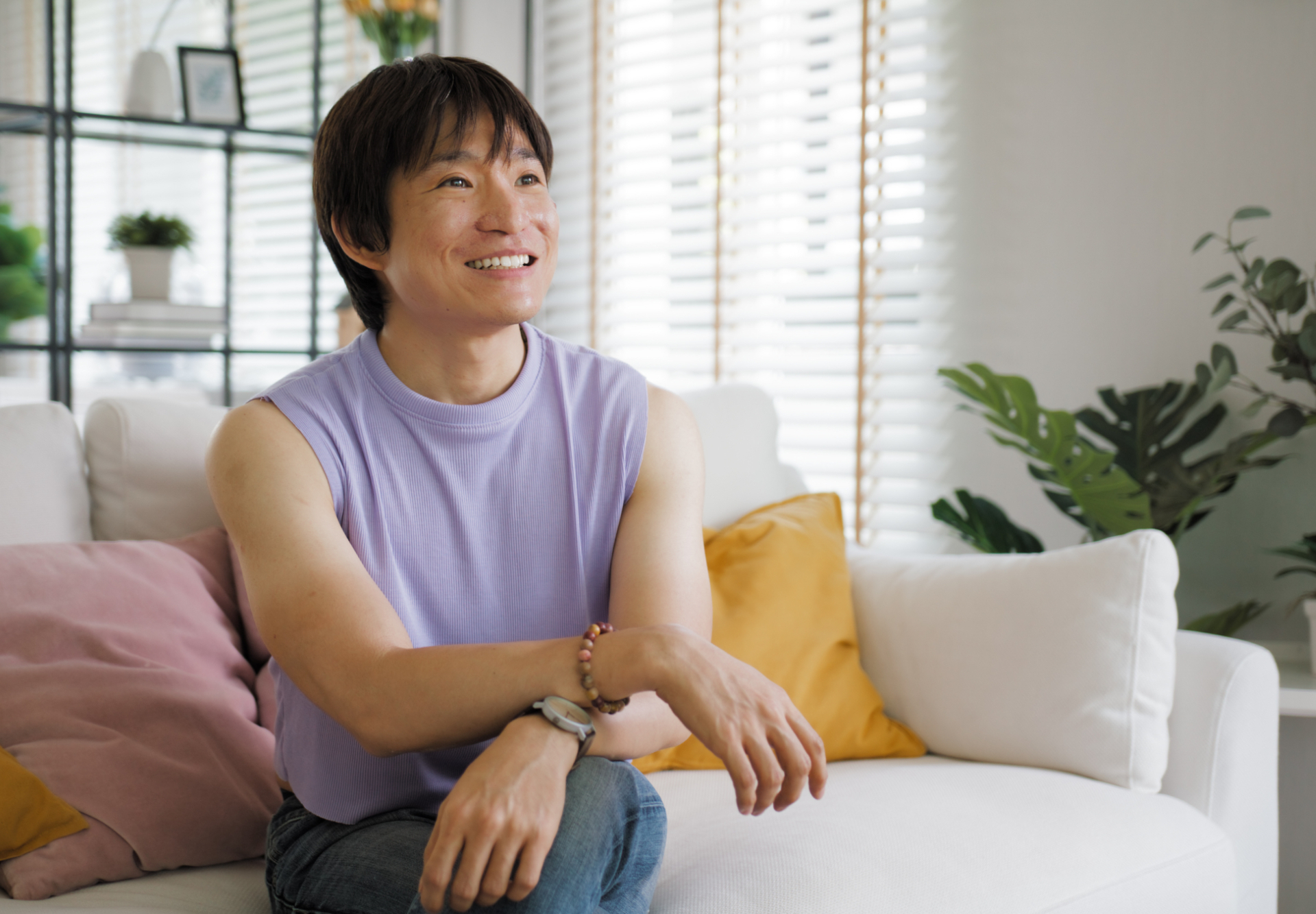 Queer nonbinary Asian person sitting on couch representing an LGBT Asian person in mental health care therapy.